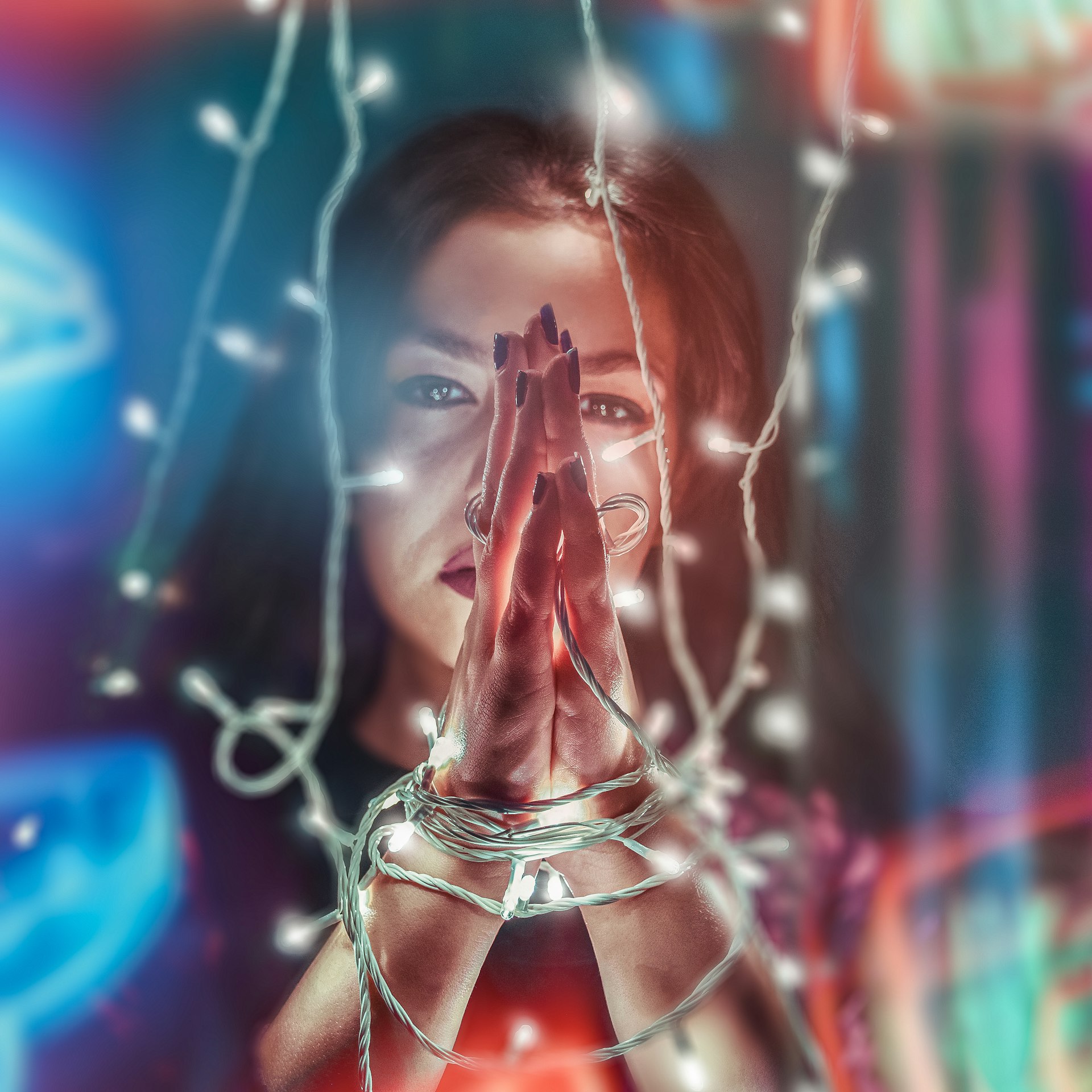 woman's hands wrapped in white string lights